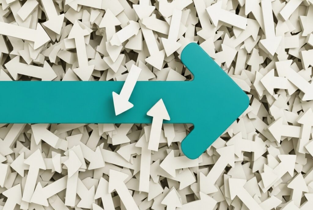 Teal right-pointing arrow among a crowd of white arrows, symbolizing direction or forward movement.