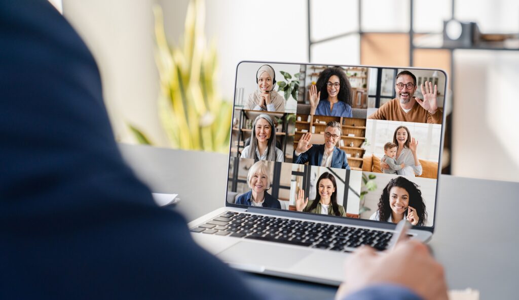 Video conference screen with nine participants waving hello in a grid layout on a laptop display.