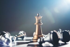 The work behind the win Gold king chess piece stands upright on a chessboard, surrounded by fallen pieces, symbolizing leadership and strategic dominance in a game.